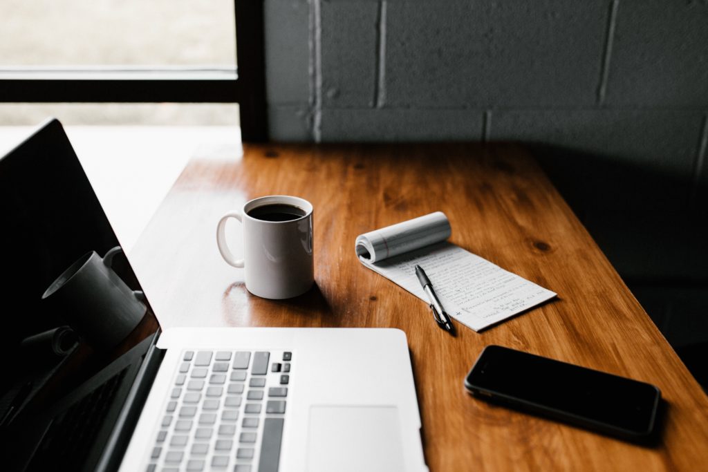 bureau met laptop kop koffie schrijfblok en mobiel